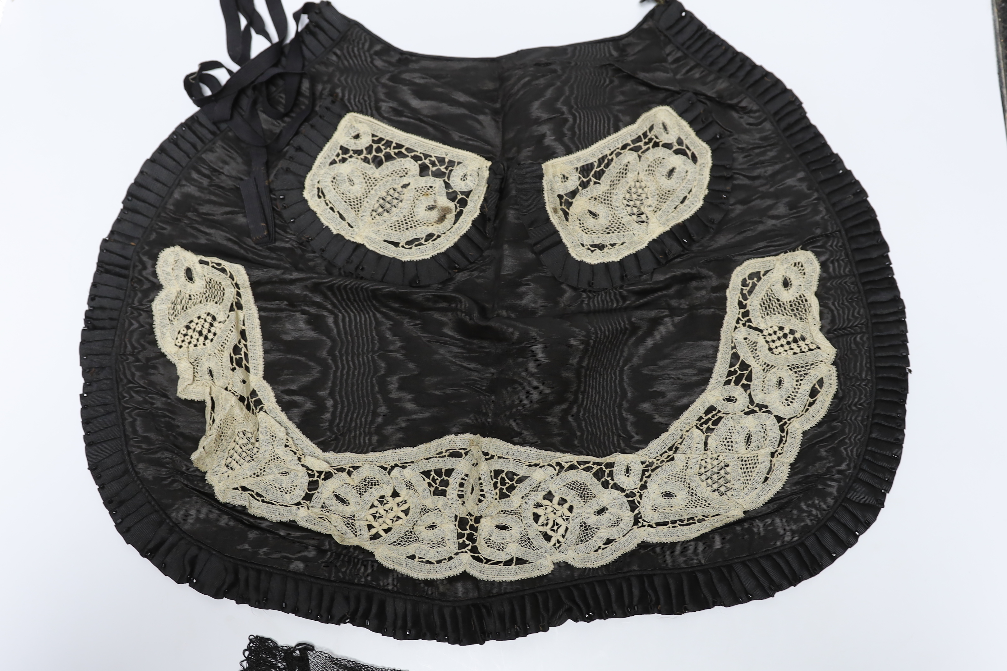 Two 19th century silk baby gowns, a ladies lace trimmed bonnet, a black satin and lace maids apron, various tatting tape lace and other table mats, etc.